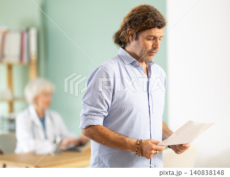 Happy man stands in reception area of clinic with her documents. 140838148