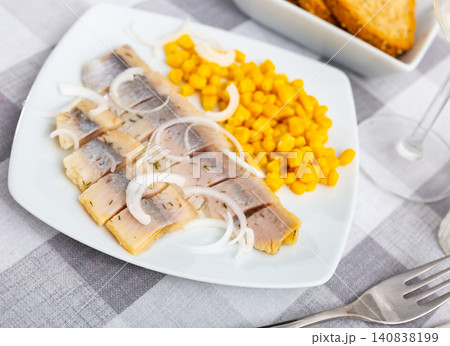 Slices of spicy marinated herring fillet with corn and onion 140838199