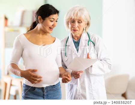 Friendly elderly doctor explaining good diagnostic results to happy woman Friendly elderly doctor explaining good diagnostic results to happy woman 140838207