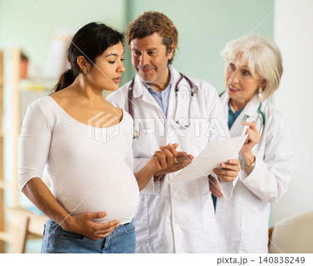 Happy pregnant woman discussing medical tests with female and male doctors Happy pregnant woman discussing medical tests with female and male doctors 140838249