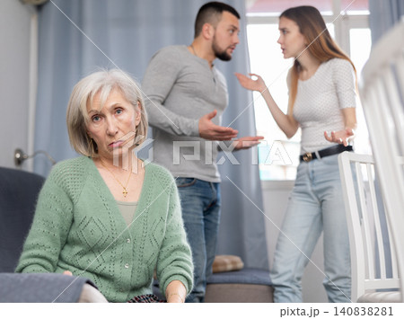 Depressed elderly woman listening her son and daughter-in-law having quarrel Depressed elderly woman listening her son and daughter-in-law having quarrel 140838281