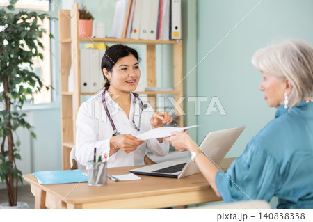 At clinic, senior woman is at doctors appointment, talking at table At clinic, senior woman is at doctors appointment, talking at table 140838338