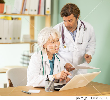 Senior woman and male doctors bent over laptop, work with medical soft 140838354