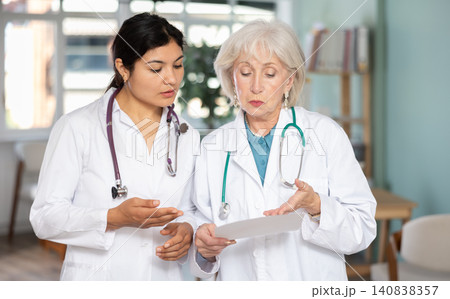 Two female doctors review or read medical documents Two female doctors review or read medical documents 140838357