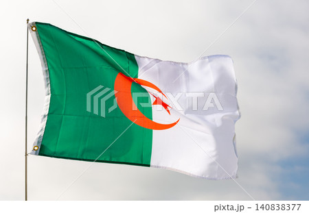 Against background of cloudy sky,white-green flag of Algeria flutters on flagpole Against background of cloudy sky,white-green flag of Algeria flutters on flagpole 140838377