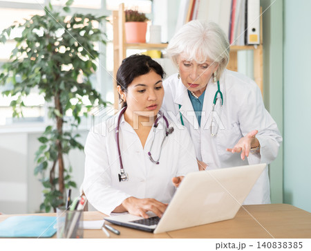 Two female doctors checking medical records on laptop Two female doctors checking medical records on laptop 140838385