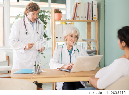 Male and female doctors explaining diagnostic results to pregnant patient 140838413
