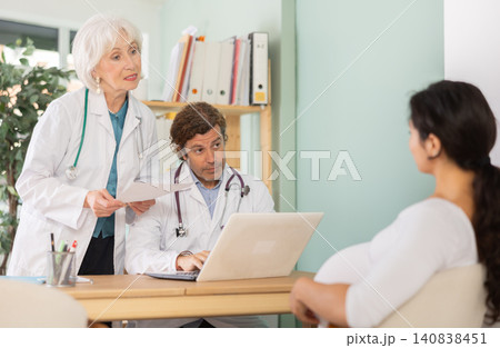 Elderly female and male doctors talking with happy pregnant woman Elderly female and male doctors talking with happy pregnant woman 140838451