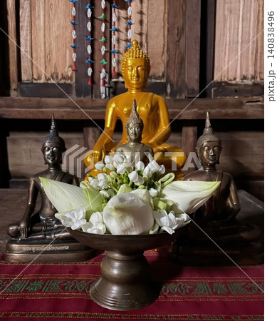 Golden Buddha Statues and White Jasmine Offerings on Wooden Altar Golden Buddha Statues and White Jasmine Offerings on Wooden Altar 140838496