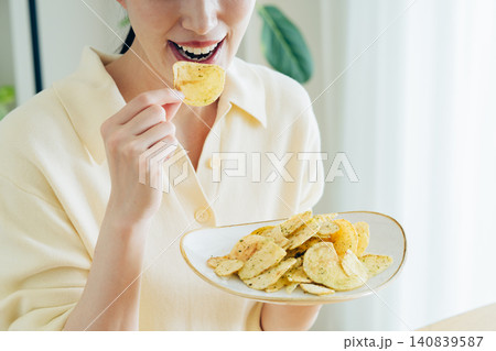 家でポテトチップスを食べる若い女性の手元 家でポテトチップスを食べる若い女性の手元 140839587