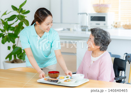 食事の介助をするヘルパーとシニア女性 140840465