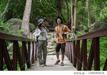 Asian woman tourist talking to boyfriend walking on wooden bridge in forest on mountain hiking trail Asian woman tourist talking to boyfriend walking on wooden bridge in forest on mountain hiking trail 140840828
