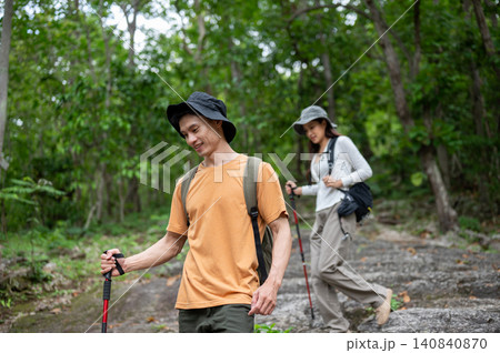 Asian male and female traveller hikers descending rocky terrain in forest path on a mountain trail Asian male and female traveller hikers descending rocky terrain in forest path on a mountain trail 140840870