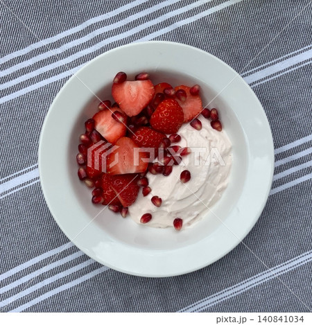 Greek yogurt served in a bowl topped with fresh colorful fruits, showcasing creamy smooth texture, vibrant natural colors, and refreshing wholesome appearance in close-up detail 140841034