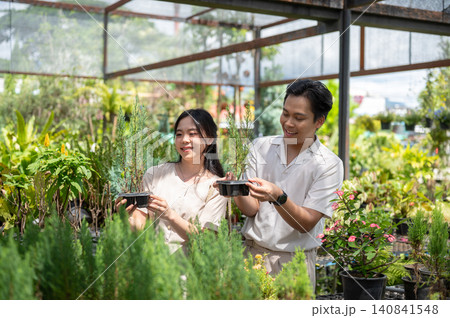 Happy asian man and woman couple choosing their own potted plant in greenhouse nursery garden center Happy asian man and woman couple choosing their own potted plant in greenhouse nursery garden center 140841548