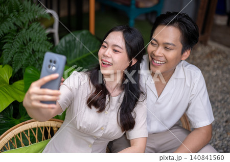Asian man and woman couple sharing a joyful selfie and enjoying time together in garden at the cafe 140841560