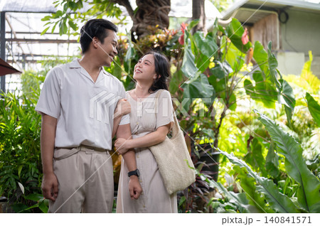 Happy asian man and woman couple linking arms while walking through in green tropical garden at cafe 140841571