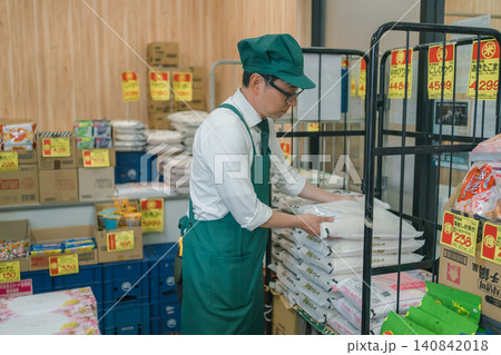 スーパーマーケットで米袋を補充する眼鏡の男性店員 スーパーマーケットで米袋を補充する眼鏡の男性店員 140842018