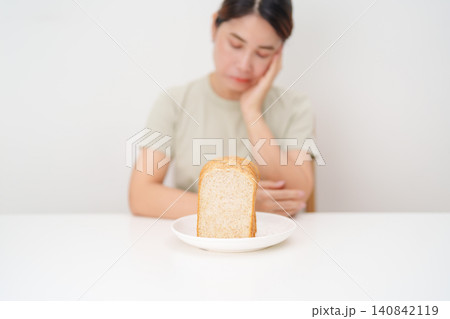 Unhappy woman disgust gesture and Bored to eat bread. concept of gluten intolerance, gluten sensitivity, carb loading concerns, or a disliking for unhealthy dietary habits Unhappy woman disgust gesture and Bored to eat bread. concept of gluten intolerance, gluten sensitivity, carb loading concerns, or a disliking for unhealthy dietary habits 140842119