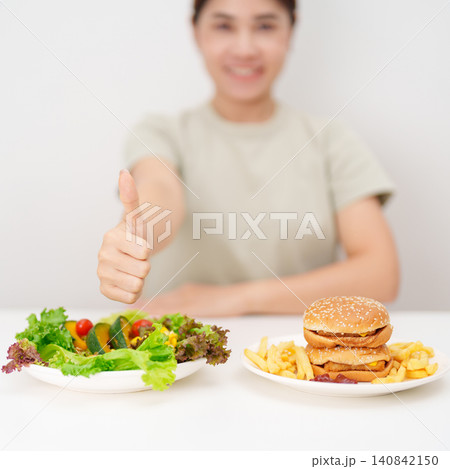 happy woman choose vegetables Salad and thumbs up gesture. Healthy and Unhealthy Food Choice, Calories and Nutrition of vegetables and Hamburger. dieting, weight loss control, junk food and lifestyle happy woman choose vegetables Salad and thumbs up gesture. Healthy and Unhealthy Food Choice, Calories and Nutrition of vegetables and Hamburger. dieting, weight loss control, junk food and lifestyle 140842150