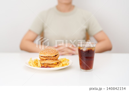 happy woman with Juicy beef burger with melted cheddar cheese, potato chips and carbonated Soft drinks. Unhealthy, High calorie, Fast food craving, Obesity, diet, weight loss, junk food and lifestyle 140842154