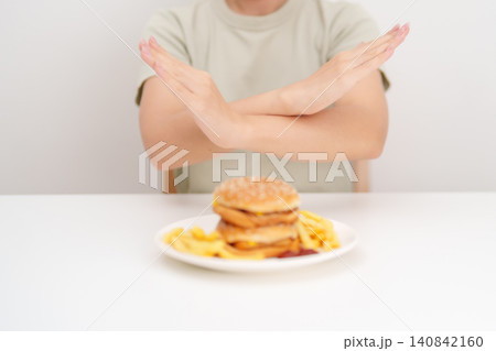 Unhappy woman showing Rejecting and refusing with Juicy beef burger, potato chips and carbonated Soft drinks. Unhealthy, High calorie, Fast food craving, Obesity, diet, weight loss and junk food 140842160