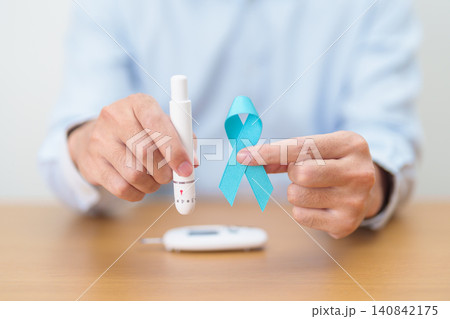 Hand show Blue Ribbon and digital blood glucose meter with lancet pen. high blood sugar level, November World Diabetes Day, Awareness month, Glycemia,, Hyperglycemia and insulin testing and checking 140842175