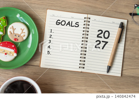 2027 GOAL with notebook, black coffee cup, Christmas cookies and pen on wood table. Xmas, Happy New Year, Resolution, To do list, Strategy and Plan concept 2027 GOAL with notebook, black coffee cup, Christmas cookies and pen on wood table. Xmas, Happy New Year, Resolution, To do list, Strategy and Plan concept 140842474