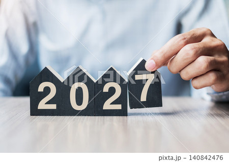 Businessman hands holding 2027 Happy New Year with house model on table office. New House, Financial, Property insurance, real estate, savings and New Year Resolution concepts Businessman hands holding 2027 Happy New Year with house model on table office. New House, Financial, Property insurance, real estate, savings and New Year Resolution concepts 140842476