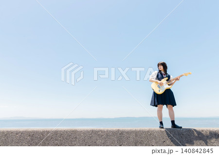 海辺でエレキギターを演奏する女子高校生 140842845