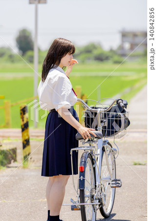 田園風景で自転車を押しながら考え事をする女子高校生 田園風景で自転車を押しながら考え事をする女子高校生 140842856