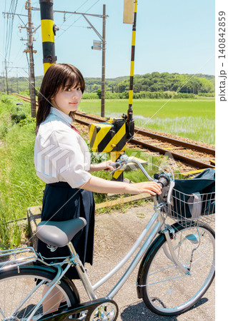 田園の踏切で自転車を押して待つ女子高校生 田園の踏切で自転車を押して待つ女子高校生 140842859