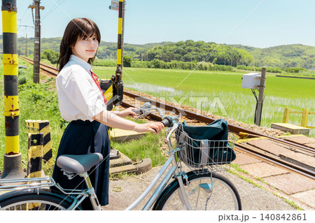 田園の踏切で自転車を押して待つ女子高校生 田園の踏切で自転車を押して待つ女子高校生 140842861