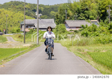田園風景の通学路を自転車で走る女子高校生 田園風景の通学路を自転車で走る女子高校生 140842870