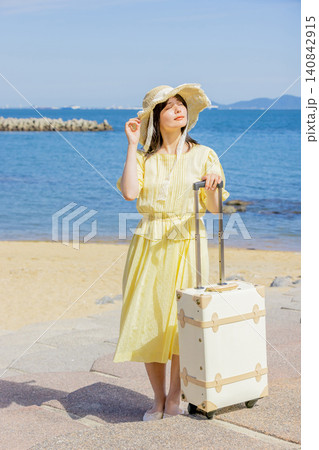 海辺のリゾートでスーツケースとともに夏を満喫する若い女性 140842915
