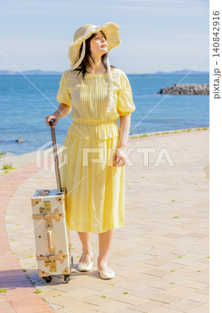 海辺のリゾートでスーツケースとともに夏を満喫する若い女性 140842916