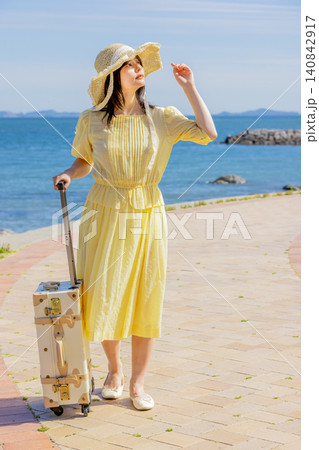 海辺のリゾートでスーツケースとともに夏を満喫する若い女性 140842917