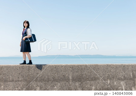 海辺の防波堤に立つ女子高校生と青空のコピースペース 海辺の防波堤に立つ女子高校生と青空のコピースペース 140843006