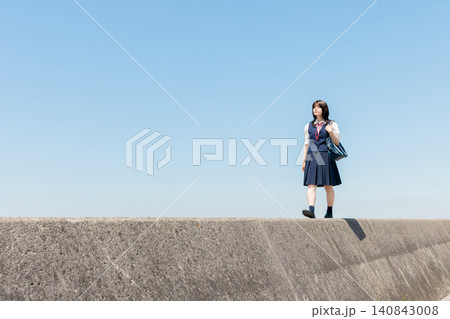 青空の下、防波堤を歩く女子高校生と広がるコピースペース 青空の下、防波堤を歩く女子高校生と広がるコピースペース 140843008