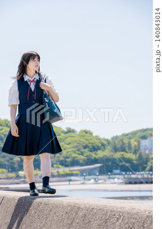 海辺の防波堤を歩く女子高校生と夏の青空 140843014