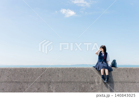 海辺の防波堤に座る女子高校生と青空のコピースペース 海辺の防波堤に座る女子高校生と青空のコピースペース 140843025