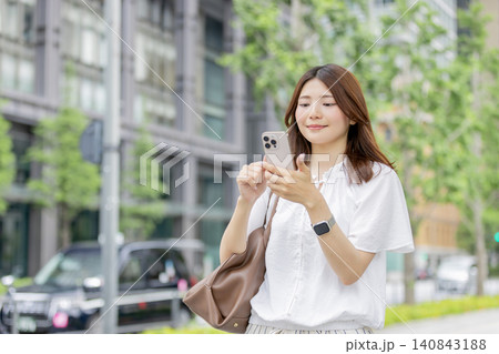 オフィス街でスマートフォンを使う笑顔の日本人女性 140843188
