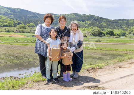 里山の水田で収穫物を手に笑顔を見せる三世代の日本人女性と子供 里山の水田で収穫物を手に笑顔を見せる三世代の日本人女性と子供 140843269
