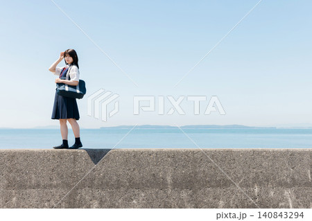 海辺の防波堤に立つ女子高校生と青空のコピースペース 海辺の防波堤に立つ女子高校生と青空のコピースペース 140843294