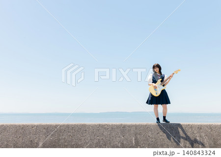 海辺でエレキギターを演奏する女子高校生 140843324