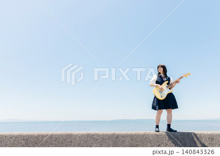 海辺でエレキギターを演奏する女子高校生 140843326