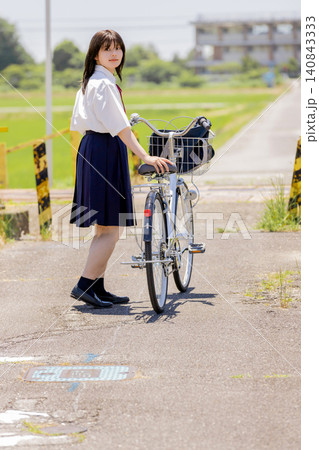 自転車を押しながら振り返る女子高校生の通学シーン　 140843333