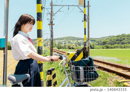 田園の踏切で自転車を押して待つ女子高校生 田園の踏切で自転車を押して待つ女子高校生 140843335