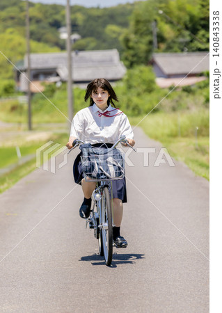 田園風景の通学路を自転車で走る女子高校生 田園風景の通学路を自転車で走る女子高校生 140843338