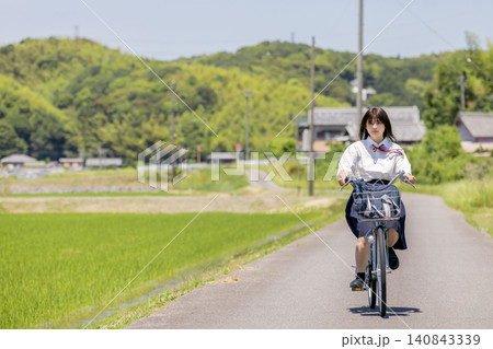 田園風景の通学路を自転車で走る女子高校生 田園風景の通学路を自転車で走る女子高校生 140843339